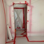 Room undergoing asbestos remediation marked with red tape.