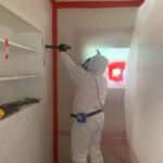 Room undergoing asbestos remediation marked with red tape.