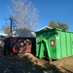 Disposal containers outside covered in tarps containing products of an asbestos removal.