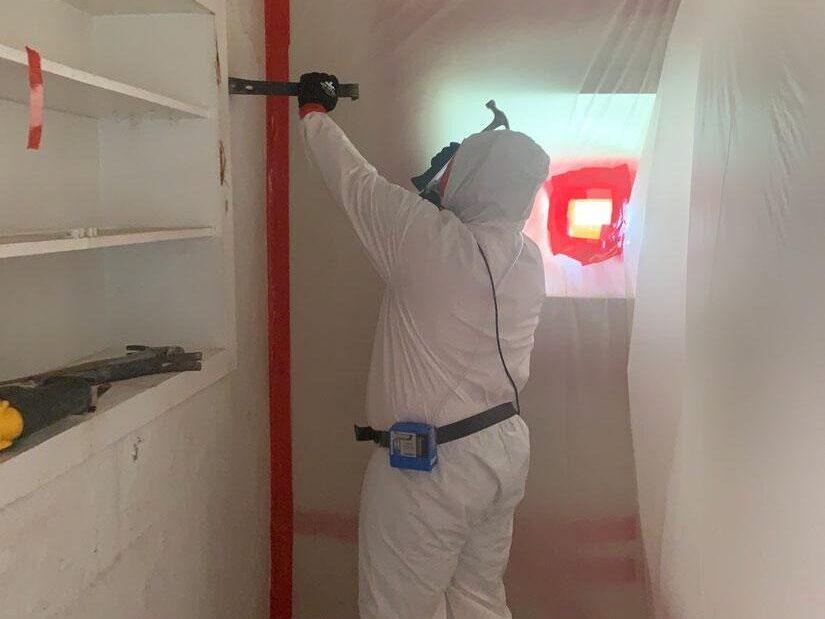 Room undergoing asbestos remediation marked with red tape.
